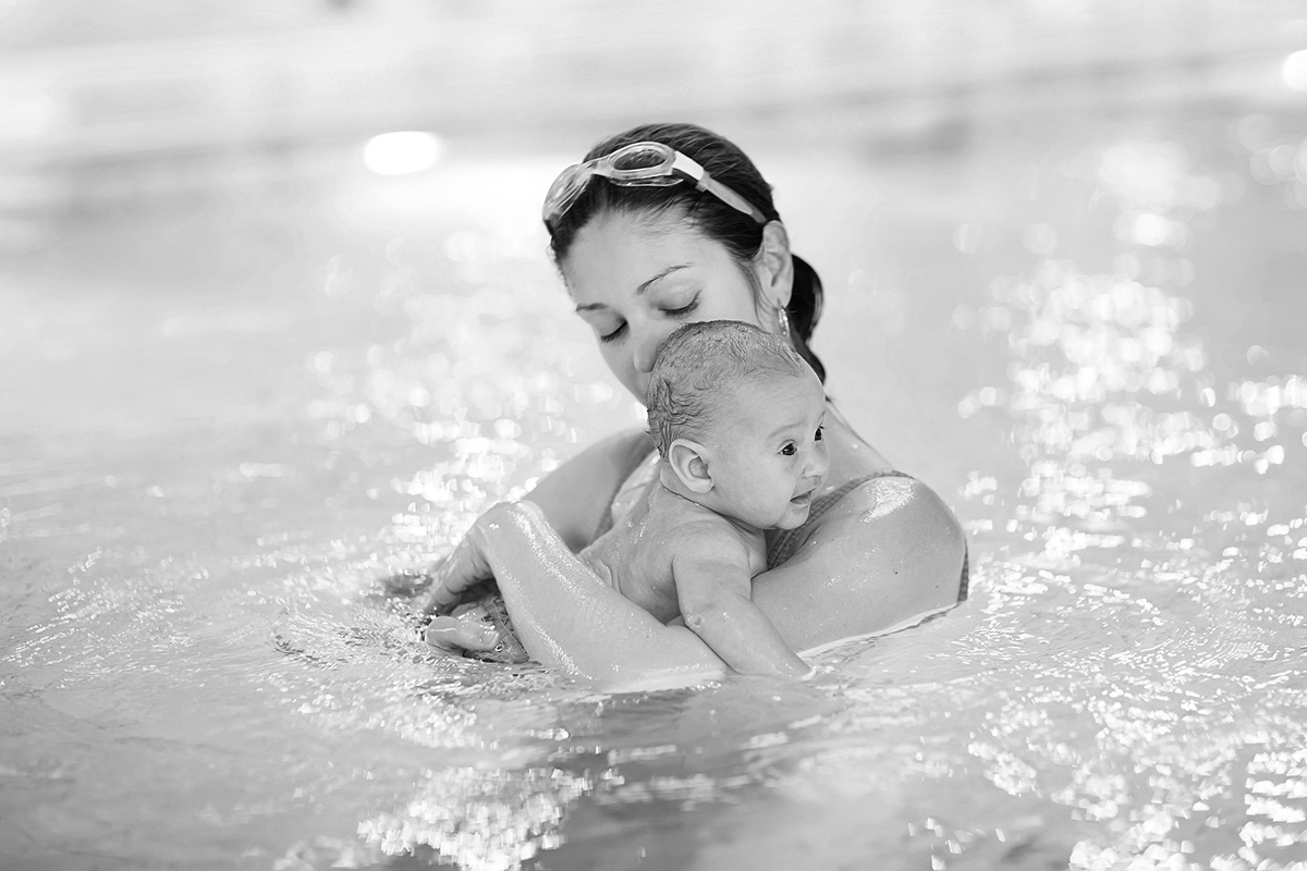 Young mother and her newborn baby son having fun in a swimming p